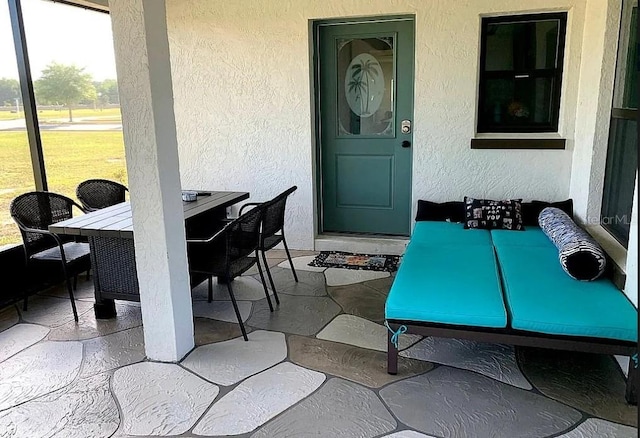 view of exterior entry with outdoor dining space, a patio area, and stucco siding