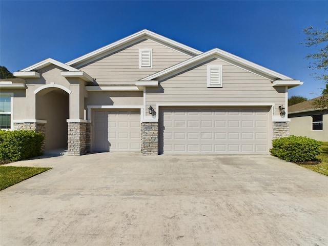 view of front of property featuring a garage, stone siding, and driveway