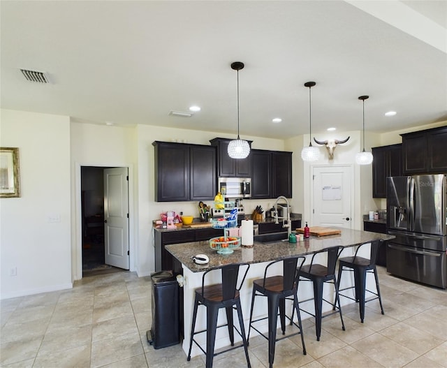 kitchen with appliances with stainless steel finishes, a sink, a center island with sink, and a kitchen breakfast bar