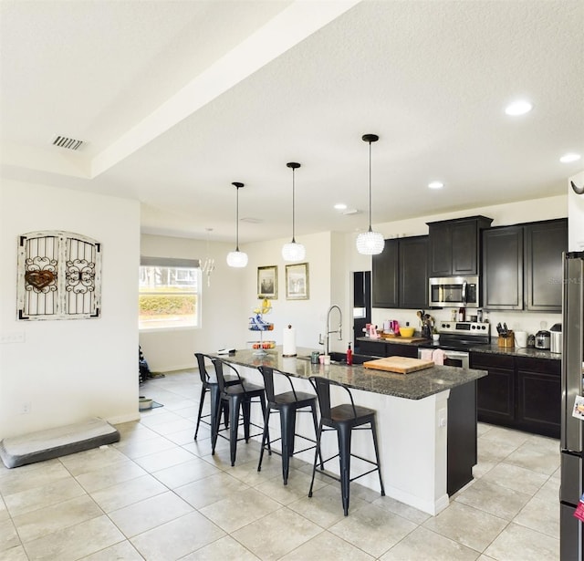 kitchen with a center island with sink, a breakfast bar area, visible vents, appliances with stainless steel finishes, and a sink