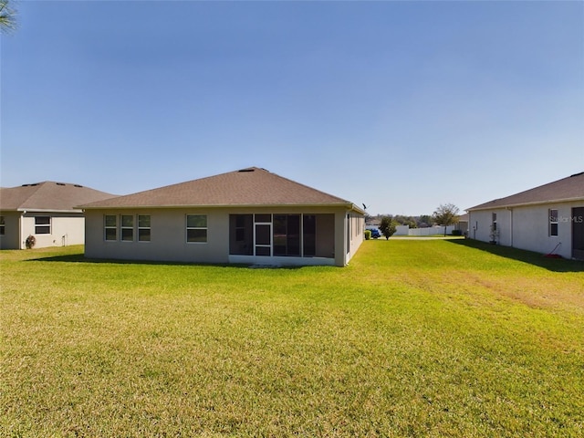 rear view of property featuring a yard, a sunroom, and stucco siding