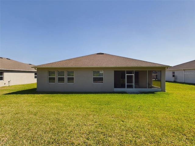 back of property with a lawn, a sunroom, and stucco siding