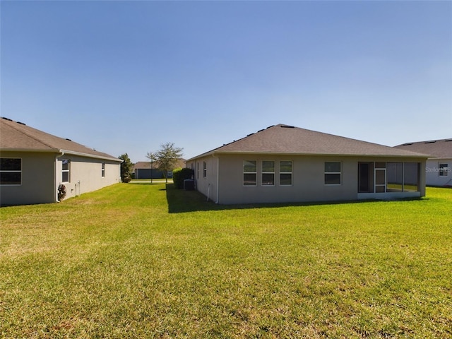 rear view of house with stucco siding and a yard