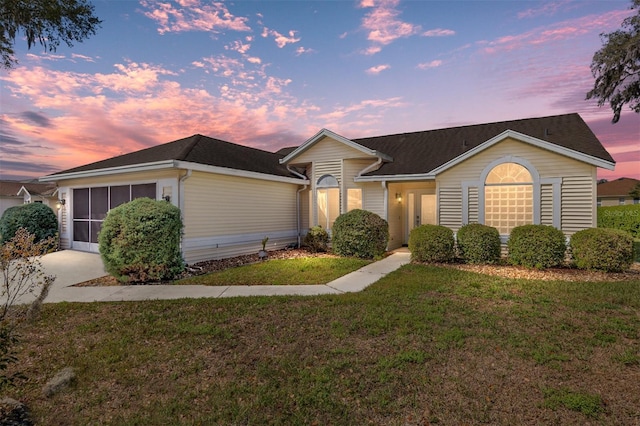 single story home featuring a sunroom and a yard