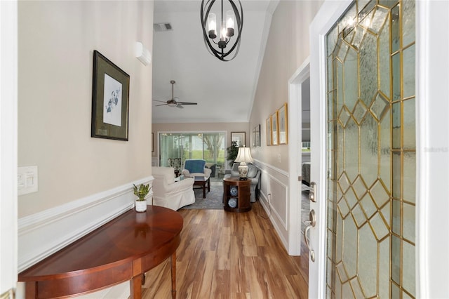 foyer entrance with visible vents, wainscoting, wood finished floors, crown molding, and a decorative wall