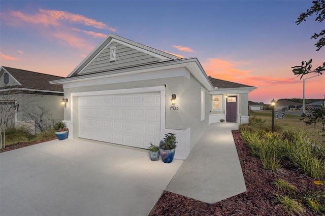 ranch-style home with driveway, an attached garage, and stucco siding