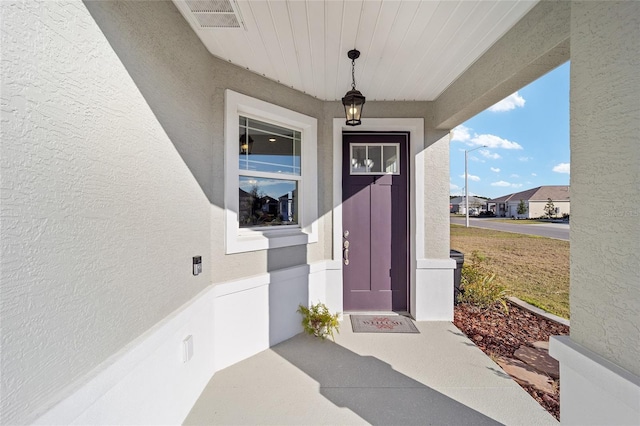 doorway to property featuring visible vents and stucco siding