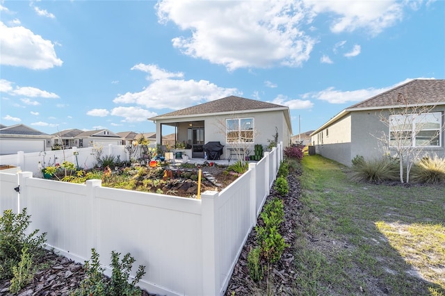 rear view of house with a patio area, a fenced backyard, a yard, and stucco siding