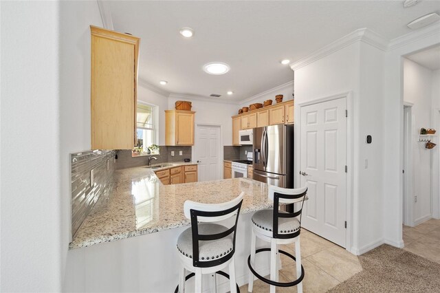 kitchen featuring white appliances, decorative backsplash, ornamental molding, a peninsula, and light brown cabinetry