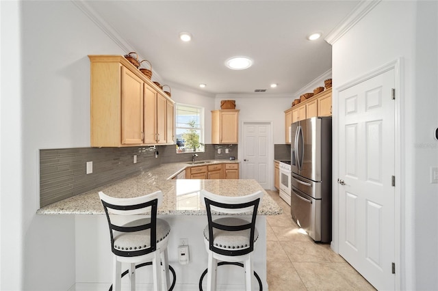 kitchen with white gas stove, light brown cabinets, a peninsula, a sink, and stainless steel fridge with ice dispenser