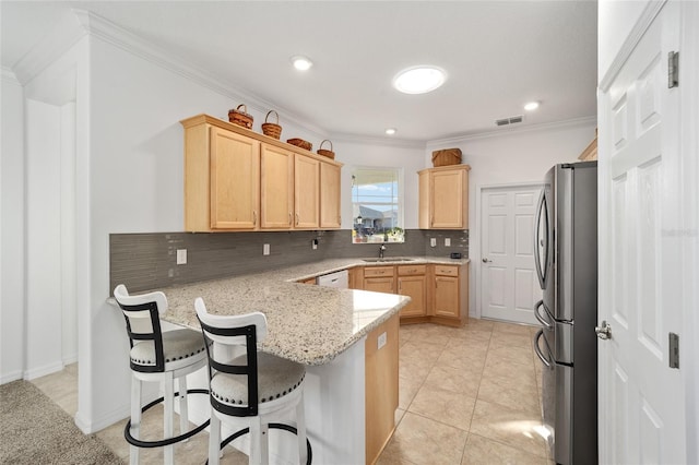 kitchen featuring a peninsula, visible vents, freestanding refrigerator, decorative backsplash, and light brown cabinetry