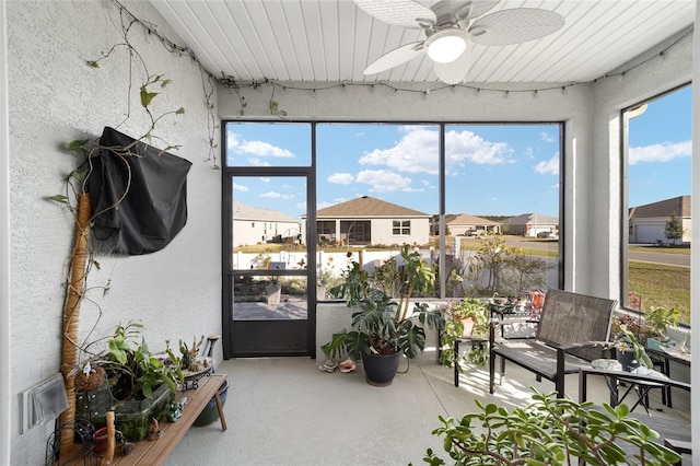 sunroom featuring ceiling fan and a residential view