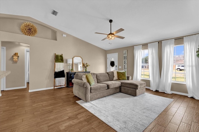 living area featuring baseboards, visible vents, arched walkways, lofted ceiling, and wood finished floors