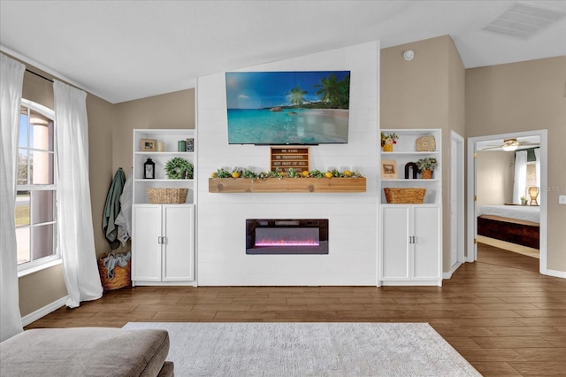 unfurnished living room featuring a large fireplace, baseboards, visible vents, lofted ceiling, and wood finished floors