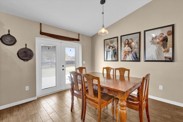 dining area featuring french doors, vaulted ceiling, baseboards, and wood finished floors