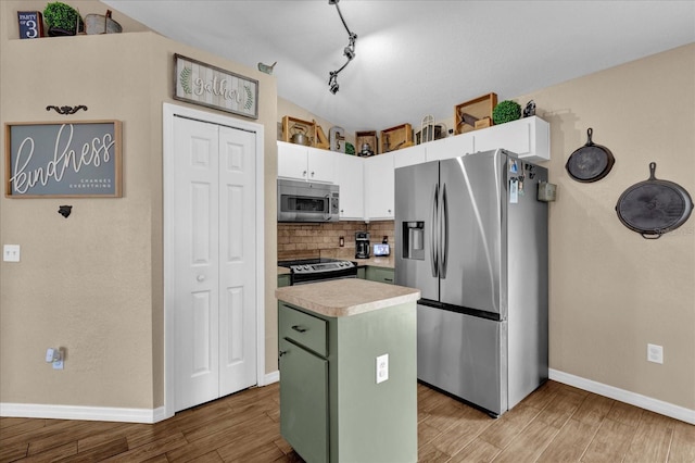 kitchen with lofted ceiling, light wood-style flooring, a center island, stainless steel appliances, and light countertops