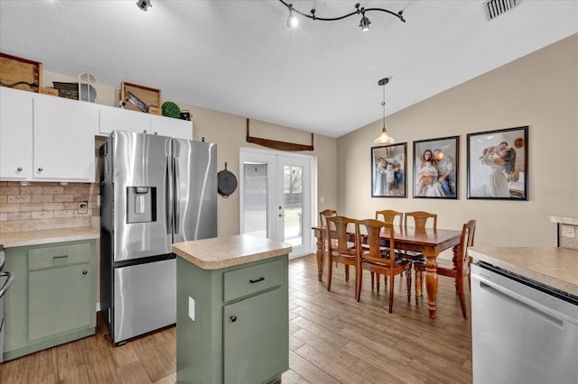 kitchen with appliances with stainless steel finishes, vaulted ceiling, french doors, light wood-type flooring, and green cabinetry