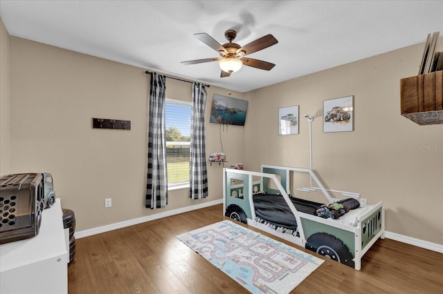 bedroom featuring wood finished floors, a ceiling fan, and baseboards