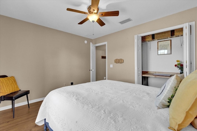 bedroom featuring wood finished floors, a ceiling fan, visible vents, baseboards, and a closet