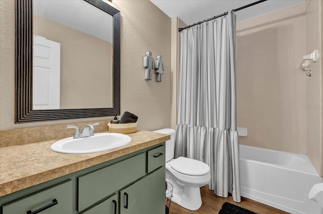 full bath with a textured wall, toilet, shower / tub combo, wood finished floors, and vanity