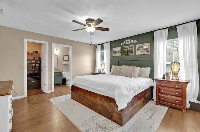 bedroom with ensuite bath, multiple windows, and wood finished floors