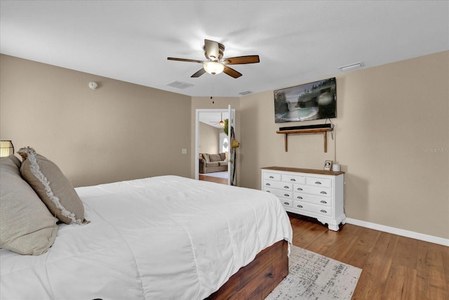 bedroom featuring a ceiling fan, baseboards, visible vents, and wood finished floors