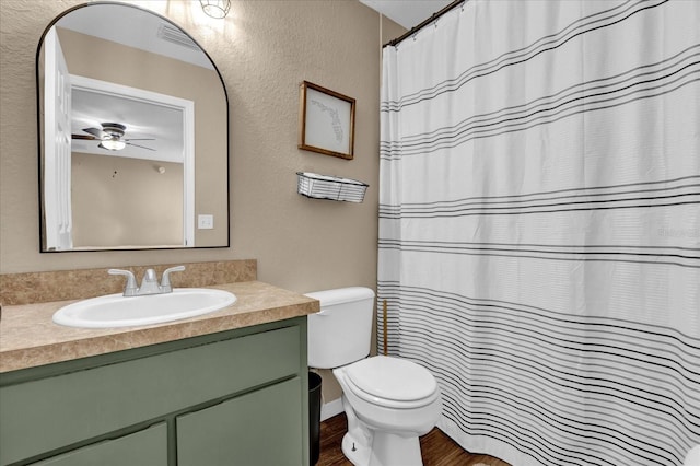 full bathroom with ceiling fan, a textured wall, toilet, wood finished floors, and vanity