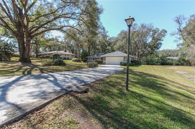 single story home featuring an attached garage, a front lawn, and concrete driveway