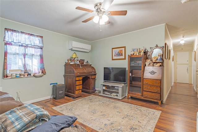 living room with ceiling fan, a wall unit AC, wood finished floors, baseboards, and ornamental molding