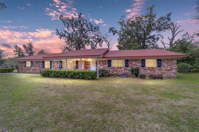 ranch-style house with metal roof, brick siding, and a front yard