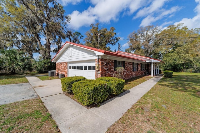 view of side of home featuring a garage, central AC, brick siding, a yard, and concrete driveway