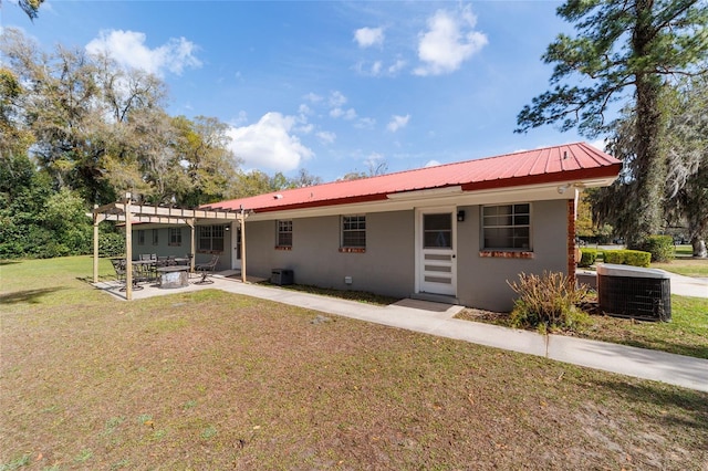 back of property with a lawn, a patio, metal roof, cooling unit, and stucco siding