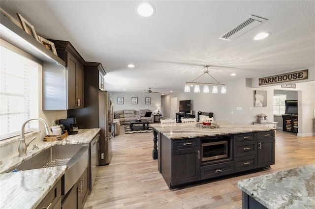 kitchen with visible vents, appliances with stainless steel finishes, open floor plan, light wood-style floors, and a sink