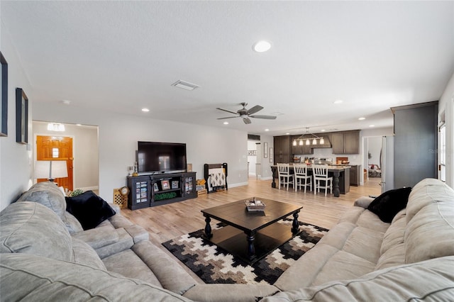 living room featuring baseboards, light wood finished floors, visible vents, and recessed lighting