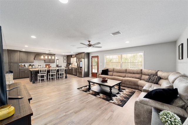 living area with light wood finished floors, recessed lighting, visible vents, ceiling fan, and a textured ceiling