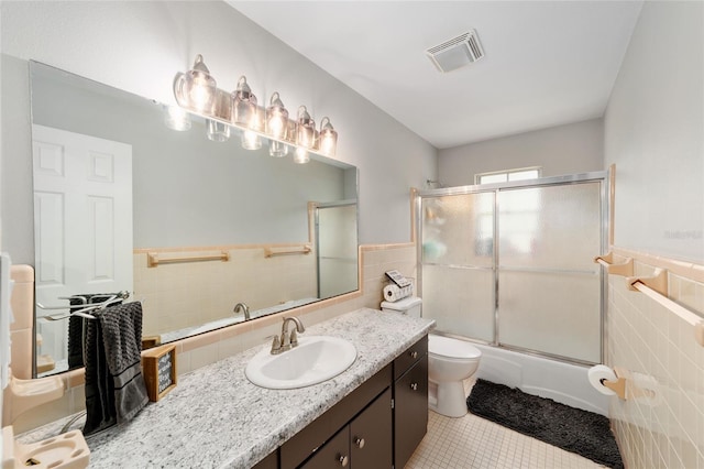 full bathroom featuring toilet, tile patterned floors, visible vents, and tile walls