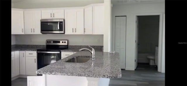 kitchen featuring appliances with stainless steel finishes, white cabinets, a sink, and light stone counters