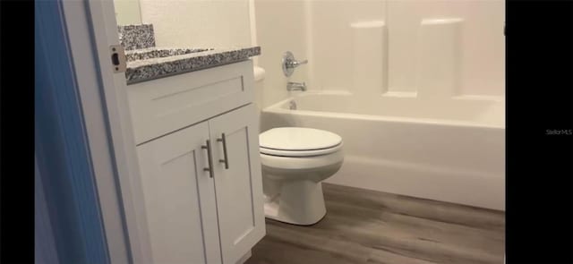 bathroom featuring  shower combination, vanity, toilet, and wood finished floors