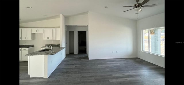 kitchen featuring a sink, white cabinetry, baseboards, vaulted ceiling, and dark wood-style floors