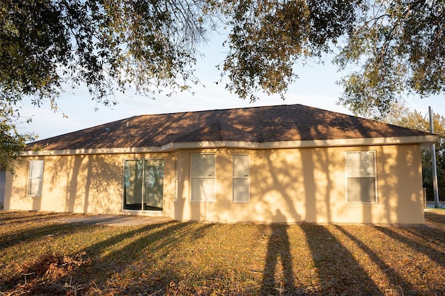 back of property with roof with shingles and stucco siding