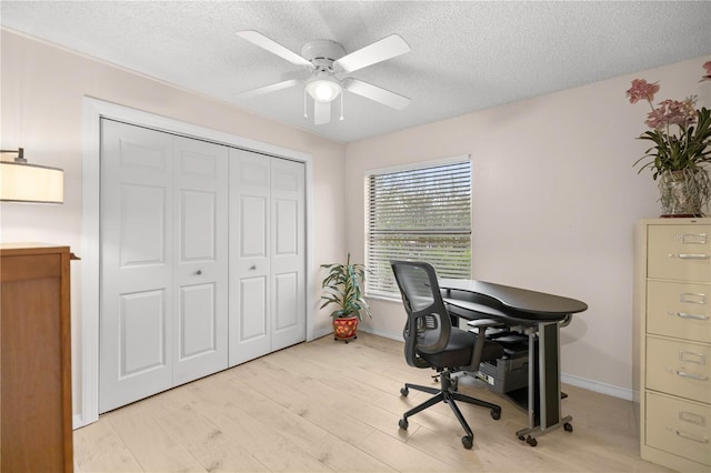 office space with light wood-style floors, baseboards, a ceiling fan, and a textured ceiling