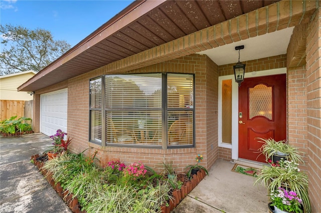 entrance to property featuring a garage, driveway, and brick siding