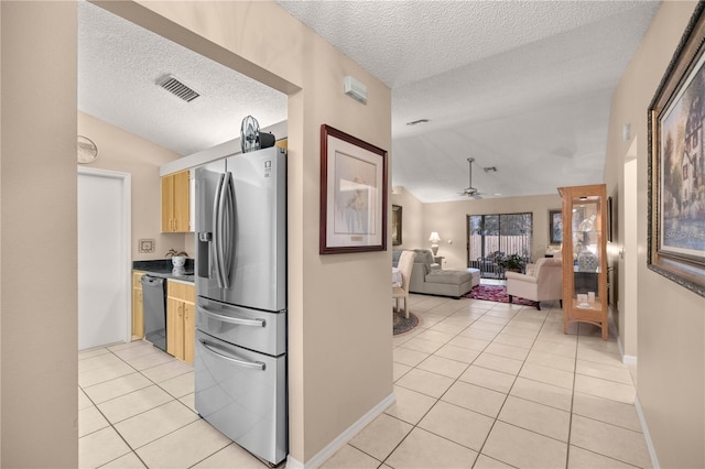 kitchen featuring black dishwasher, stainless steel fridge, visible vents, and lofted ceiling