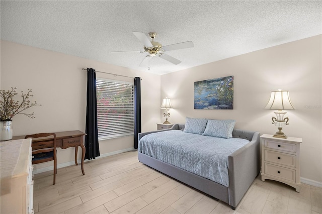 bedroom with a ceiling fan, baseboards, light wood-style flooring, and a textured ceiling