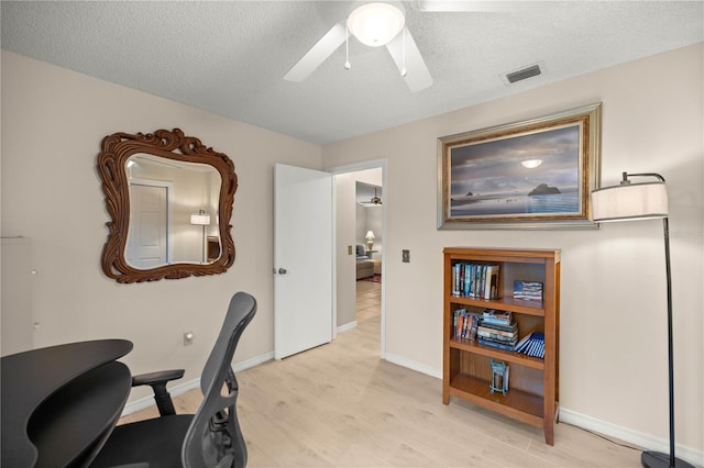 office space featuring ceiling fan, a textured ceiling, light wood-type flooring, and visible vents