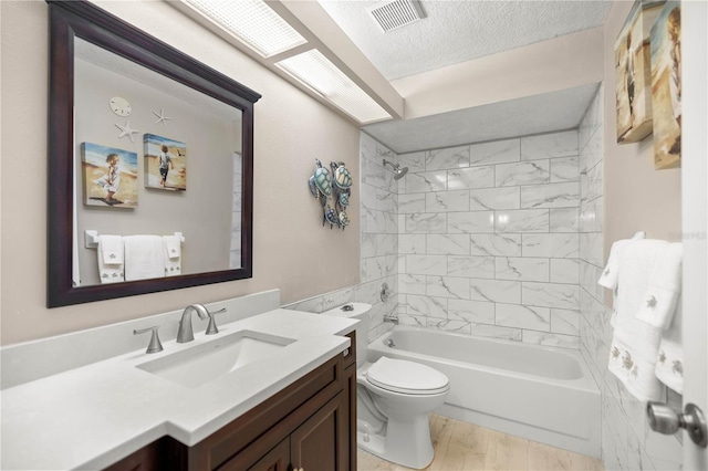 full bath with visible vents, toilet, wood finished floors, a textured ceiling, and vanity