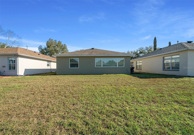 rear view of house with a lawn and stucco siding