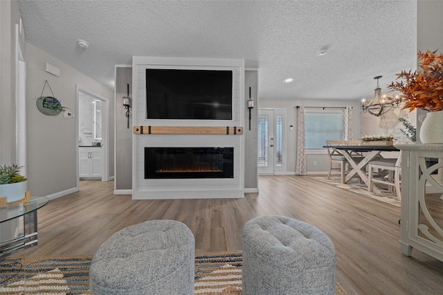 living area featuring a textured ceiling, a fireplace, wood finished floors, and baseboards