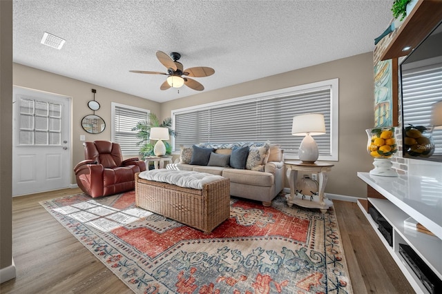 living area with baseboards, visible vents, ceiling fan, wood finished floors, and a textured ceiling