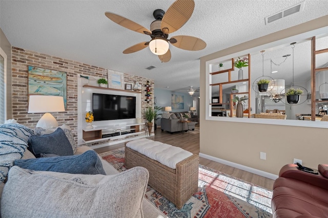 living room featuring a textured ceiling, brick wall, wood finished floors, and visible vents